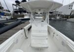 White center-console boat at a marina, viewed from the stern with a bench seat and T-top.