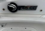 Rear of a white car showing a chrome '245 CC' badge and circular emblem on the trunk.