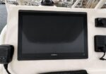 Garmin marine chartplotter display mounted on a boat console with radio and other navigation gear nearby