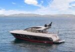 White luxury motor yacht cruising on calm blue sea with distant mountains on the horizon.
