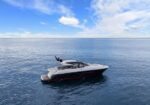 White motorboat cruising on calm blue ocean under a clear sky with a few clouds.
