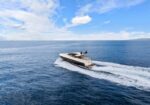 Luxurious motor yacht speeding across open blue ocean, leaving a frothy white wake behind it.