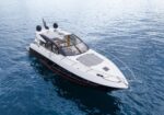 White luxury motor yacht seen from above on calm blue sea, with sun deck and open cockpit.