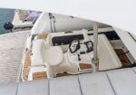 Top-down view of a luxury yacht cockpit with white leather seats, steering wheel, and navigation console.