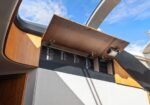 Open wooden cabinet reveals a printed menu board with items, mounted in a vehicle with a skylight overhead.