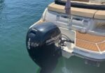 Rear view of a white motorboat with a black Mercury 150 outboard motor attached, floating in clear blue water.