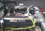 Boat engine bay featuring a MerCruiser Fresh Water Cooling System with hoses, clamps, and wiring visible behind the cooling tank.