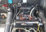 Boat engine bay with a MerCruiser freshwater cooling system, black engine block, hoses, and wiring in a boat’s engine compartment.