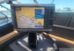 Marine cockpit with GPS/chartplotter showing coastal map and route.