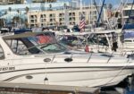 White motor yacht named 'Two Best Days' moored at a marina with other boats and buildings in the background.