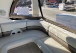 White and beige cushioned seating inside a boat cockpit with a marina visible through the windows.