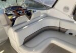 White wraparound boat seating in the cockpit with a wooden steering wheel and instrument panel visible at the helm in the background.