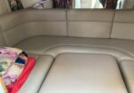 Beige leather L-shaped seating area inside a vehicle, with colorful pillows on the left.