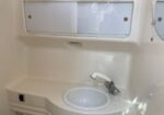 White circular sink with a curved chrome faucet set into a compact bathroom vanity, with a mirrored cabinet above.