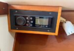 Marine stereo head unit mounted in a wooden panel, with a large round volume knob on the left, control buttons, and a digital display.