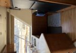 Yacht galley with wooden cabinets, double sink, and a refrigerator, view of marina through the window.