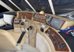 Boat cockpit with wood-grain dashboard, steering wheel, multiple gauges, and a navigation screen on the right.