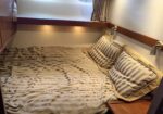 Cozy boat cabin bunk with striped beige bedding and two pillows on the lower bed.