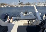 View from a boat deck looking toward a crowded marina with many yachts and palm trees in the background, sunny day.