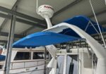 Boat stored in a covered marina with a blue canvas canopy and a Raymarine radar dome mounted on the mast arch.