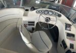 Helm of a white boat cockpit with a stainless steering wheel and multiple gauges on the dashboard.