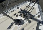 Boating cockpit deck with a winch, heavy chains, cleats, and stainless hardware visible on a white surface.”,