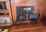 Teak-paneled boat radio station with a marine VHF transceiver and control knobs mounted in a cabinet.