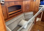 Wood-paneled boat cabin with a long gray cushioned bench and built-in cabinets along the wall.