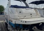 Rear view of a white motorboat on a trailer in a parking lot, blue canvas cover over cockpit and 'Lake Tahoe CA' written on the stern