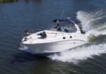 White motorboat carving through blue water, creating a foamy wake to the right.