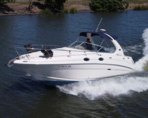 White speedboat with blue canopy speeding on a river, creating a large wake