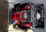 Red-coated V8 engine with a large supercharger and blue ignition wires in a vehicle engine bay.