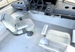 Boat cockpit interior with a stainless steering wheel, gauge panel, and white seating area.