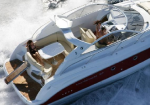 Overhead view of a white motor yacht speeding through rough water, with passengers relaxing on deck.