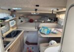 Cozy boat cabin with a kitchenette on the left and a U-shaped seating area with cushions at the rear.