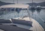 Bow of a white motorboat at a marina, with calm blue water and moored yachts in the background.