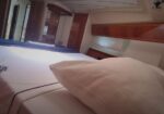Luxurious boat cabin with a white bed, pillow, and wooden storage cabinets along the wall.