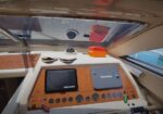 Captain's helm aboard a boat with two Raymarine displays, wood-grain panel, gauges, and navigation controls visible.