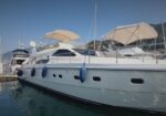 White luxury yacht docked at a marina, fenders along the hull and sunshades over the decks.