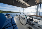 Boat cockpit with blue cushioned seating, steering wheel, and navigation controls, facing open sea and distant coastline.