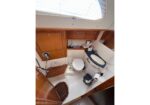 Compact boat head with toilet, sink, and wooden cabinets on teak cabinetry
