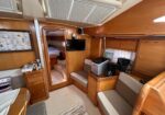 Wood-paneled boat cabin with a seating area, kitchenette with a coffee maker and toaster, and a doorway to a sleeping area.