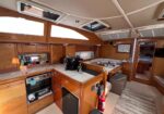 Wood-paneled yacht galley with countertop, stove and cabinets; a dining nook ahead with seating for four. (informative image)