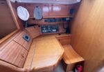 Wooden navigation station in a sailboat cabin with chart table, cushions, and radio controls.