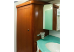 Wooden bathroom vanity with teal countertop, round sink, and mirrored cabinet above.