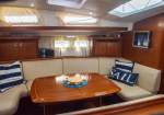 Cozy boat cabin with cream sofa, wooden table, and navy-and-white striped pillows, sunlit skylight above.
