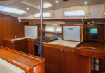 Wood-paneled boat galley with stove, refrigerator, and cabinets along a cream counter wall.