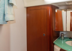 Bathroom vanity with a tall wooden cabinet beside a green countertop sink and mirrored medicine cabinet, turquoise towels hanging on the left.
