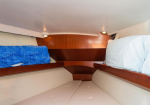 Cozy boat cabin with cushioned bunks, blue patterned blanket on the left and light blue bedding on the right, and wooden paneling in the back.