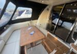 Yacht deck seating area with a wooden table and white cushioned bench; two blue ceramic fish decorations on the table.